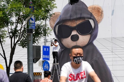 A worker installs a surveillance camera outside a mall, Friday, July 8, 2022, in Beijing. China's economic growth plunged to 0.4% over a year earlier in the latest quarter after Shanghai and other cities were shut down to fight coronavirus outbreaks, but the government said a 'stable recovery' is underway.