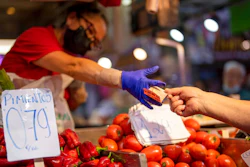 A customer pays for vegetables at the Maravillas market in Madrid, on May 12, 2022. Inflation figures for Europe will be released Friday, July 1, 2022, as Russia's war in Ukraine has worsened the worldwide surge in consumer prices. For months, inflation in the 19 countries that use the euro has risen at the fastest pace since record-keeping for the currency began.