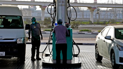 A gas station attendant fills a gas tank in Dubai, United Arab Emirates, Sunday, July 10, 2022. Mere years ago, fuel was cheaper than bottled water in the oil-rich United Arab Emirates. Now, long lines snake outside gas stations on the eve of monthly price hikes.