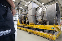 Employees stand around the turbine serviced in Canada for the Nordstream 1 natural gas pipeline in Muelheim an der Ruhr, Germany, Aug. 3, 2022. German Chancellor Olaf Scholz visited a plant by Siemens Energy where a turbine, which is at the center of a dispute between Germany and Russia over reduced gas supplies, is currently sitting in storage until it can be shipped to Russia.