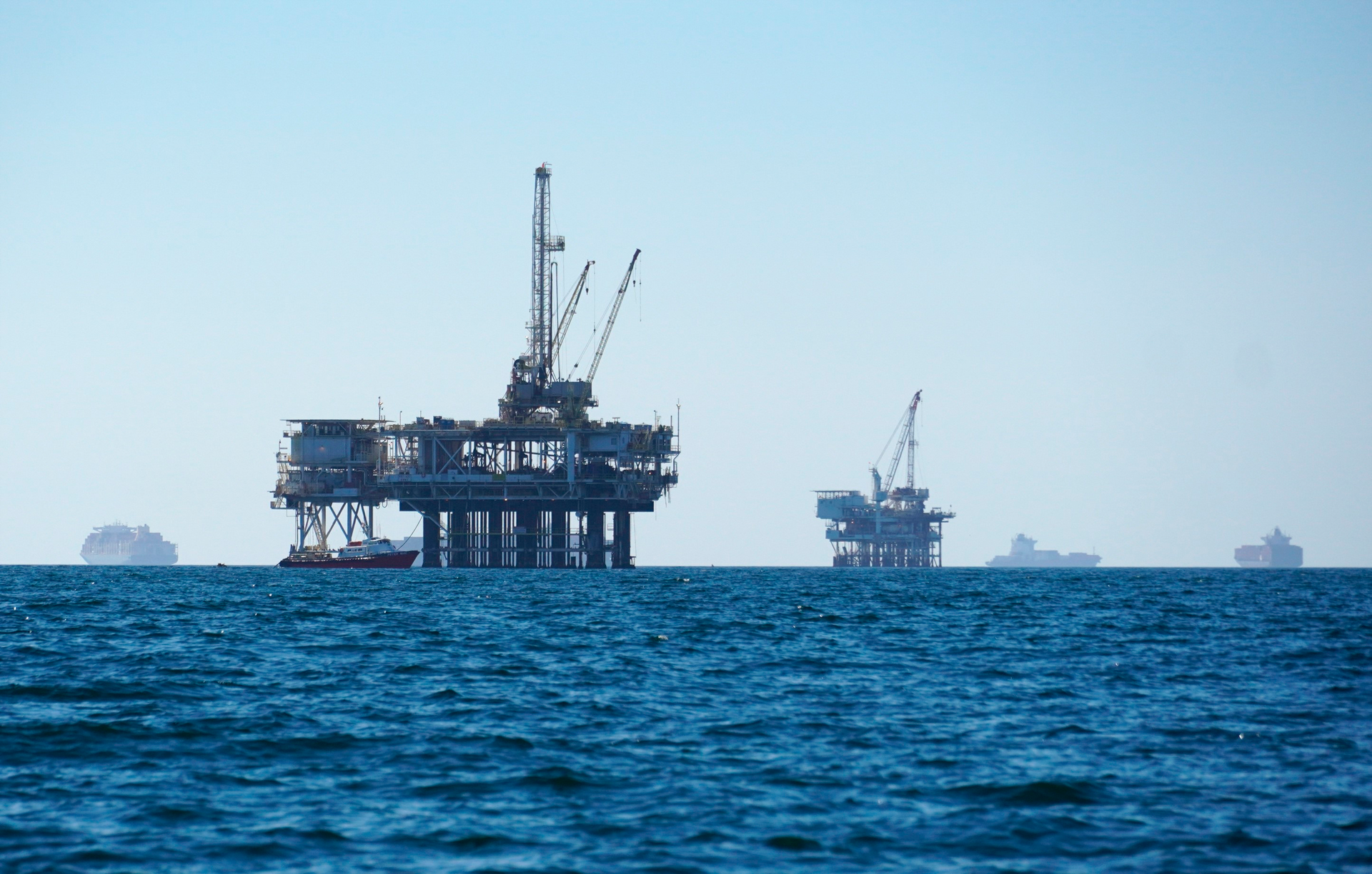 Cargo vessels are anchored offshore near oil platforms, before heading into the Los Angeles-Long Beach port on Oct. 5, 2021. The first official federal calculations of the new spending package that President Biden signed show it will slice America's carbon pollution by more than 1 billion tons by the end of the decade. The new law’s provisions that call for oil and gas leasing on federal land and water “may lead to some increase” in carbon pollution, the federal analysis said.