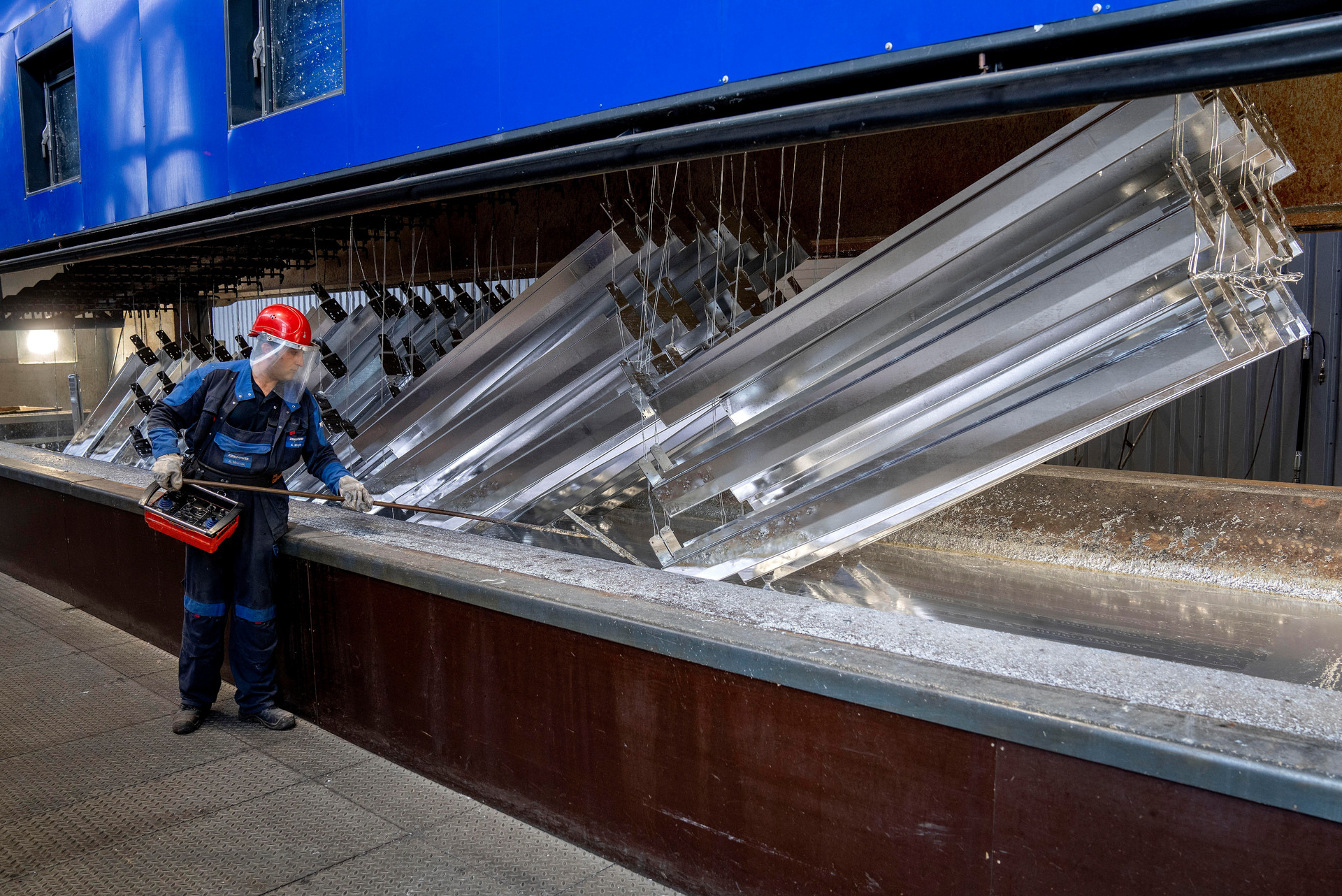 A worker moves hot-dip galvanized metal pieces at Zinkpower, Meckenheim, Germany, Aug. 18, 2022.