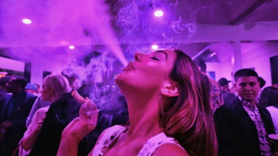 A guest takes a puff from a marijuana cigarette at the Sensi Magazine party celebrating the 420 holiday in the Bel Air section of Los Angeles on April 20, 2019.