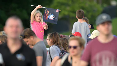 A child waves a souvenir flag while waiting on the Max Brewer Bridge to view the launch on Pad 39B for the Artemis I mission to orbit the moon at the Kennedy Space Center, Monday, Aug. 29, 2022, in Titusville, Fla. The launch was scrubbed.