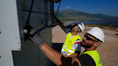 Maintenance engineers check installations at a new solar park outside the northern Greek city of Kozani on June 3, 2022. A new report has found that clean energy now provides more employment than the fossil fuel industry, reflecting the shift that efforts to tackle climate change are having on the global jobs market.
