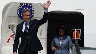 US Secretary of State Antony Blinken waves in front of US Commerce Secretary Gina Raimondo as they deplane at Benito Juarez International Airport in Mexico City.