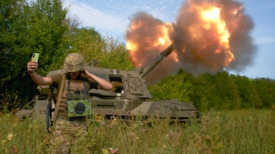 A Ukrainian soldier takes a selfie as an artillery system fires in the front line in Donetsk region, eastern Ukraine, Saturday, Sept. 3, 2022.