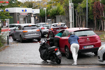 A scooter rider helps a motorist pushing his car to reach a gas station, Friday, Oct. 14, 2022 in Nanterre, outside Paris. Strikes in the French refineries of TotalEnergies group were still going on Friday, heavily disrupting fuel supplies as hard-left CGT union rejected a deal over pay rise that has been found between the energy giant and two other more moderate unions.
