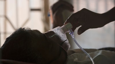 A relative adjusts the oxygen mask of a tuberculosis patient at a TB hospital on World Tuberculosis Day in Hyderabad, India, March 24, 2018.