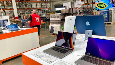 A sales associate helps a prospective customer as laptops sit on display in a Costco warehouse, Aug. 15, 2022, in Sheridn, Colo. Americans picked up their spending a bit in August from July even as surging inflation on household necessities like rent and food take a toll on household budgets. The U.S. retail sales rose an unexpected 0.3% last month, from being down 0.4% in July, the Commerce Department said Thursday., Sept. 15, 2022.