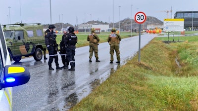 Police and personnel from the Home Guard stand guard outside the land plant of the Ormen Lange gas field after a person called in a bomb threat against the plant, in Aukra, Norway, Thursday Oct. 13, 2022.