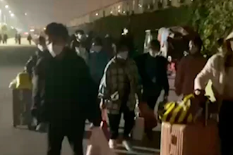 In this photo taken from video footage and released by Hangpai Xingyang, people with suitcases and bags are seen leaving from a Foxconn compound in Zhengzhou in central China's Henan Province on Saturday, Oct. 29, 2022.