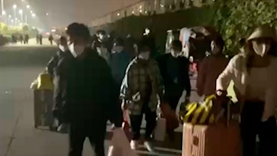 In this photo taken from video footage and released by Hangpai Xingyang, people with suitcases and bags are seen leaving from a Foxconn compound in Zhengzhou in central China's Henan Province on Saturday, Oct. 29, 2022.