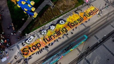 Climate activists lie after painting 'stop funding fossil fuels' on the square in front of the Euro sign in Frankfurt, during 'Fridays for Future' event, Oct. 29, 2021.