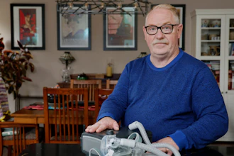 Jeffrey Reed, who experienced persistent sinus infections and two bouts of pneumonia while using a Philips CPAP machine, poses with the device at his home Thursday, Oct. 20, 2022, in Marysville, Ohio.