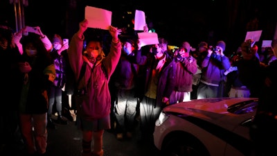 Protesters hold up blank papers and chant slogans as they march in protest in Beijing, Sunday, Nov. 27, 2022.