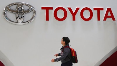A boy looks up at the logo of Toyota Motor Corp. at its gallery in Tokyo, Jan. 15, 2020. Toyota said Tuesday, Nov. 1, 2022, that its profit fell 31% in the last quarter as a shortage of computer chips offset foreign exchange gains from a weaker yen.