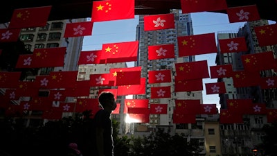 A man walks past Chinese and Hong Kong flags to celebrate the 25th anniversary of Hong Kong handover to China, in Hong Kong, on June 24, 2022. World Trade Organization arbitrators concluded Wednesday, Dec. 21, 2022, that the United States was out of line in requiring that products from Hong Kong be labeled as “Made in China,” a move that was part of Washington's response to a crackdown on pro-democracy protests there in 2019-2020.