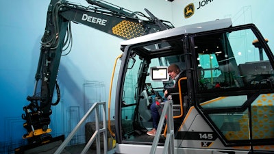 People look at a John Deere electric excavator at the John Deere booth during the CES tech show Friday, Jan. 6, 2023, in Las Vegas.