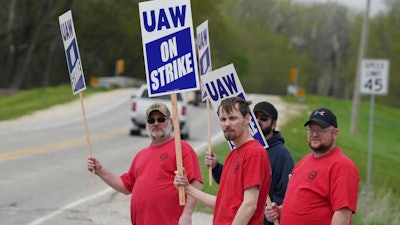 Members of United Auto Workers Local 807 carry picket signs after going on strike, May 2, 2022, at a CNH plant in Burlington, Iowa.