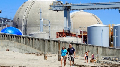 People walk on the sand near the shuttered San Onofre nuclear power plant in San Clemente, Calif., on June 30, 2011. The U.S. government has long struggled to find a permanent solution for storing or disposing of spent nuclear fuel generated by the nation's commercial nuclear power plants, and opposition in the Southwestern U.S. is flaring up again as New Mexico lawmakers debated a bill that would ban construction of such a facility without state consent.