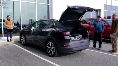 A couple shops for a Volkswagen ID.4 electric vehicle while assisted by a salesman at right, at a new car dealership, Monday, Feb. 6, 2023, in Manchester, N.H. On Wednesday the Commerce Department releases U.S. retail sales data for January.