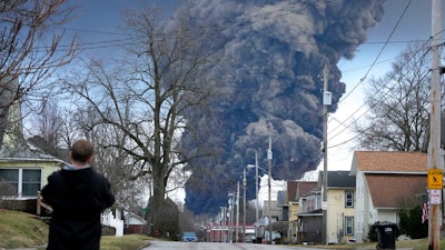 A man takes photos as a black plume rises over East Palestine, Ohio, as a result of a controlled detonation of a portion of the derailed Norfolk and Southern trains Monday, Feb. 6, 2023.