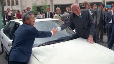 Britain's Trade Secretary Lord Young shakes hands with Shoichiro Toyoda, then president of Toyota Motors, right, over the hood of a Toyota car in London Tuesday, April 18, 1989. Toyoda, who as a son of the company's founder oversaw Toyota's expansion into international markets has died. He was 97.