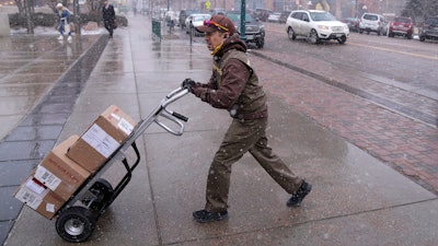 A United Parcel service driver wheels a delivery into the El Paso County, Colo., courthouse on Wednesday, Feb. 22, 2023, in Colorado Springs, Colo. On Friday, the U.S. government issues the March jobs report.