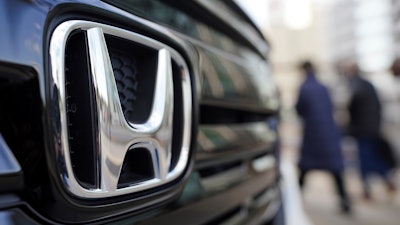 People walk near the logo of Honda Motor Company at a showroom Tuesday, Feb. 8, 2022, in Tokyo.