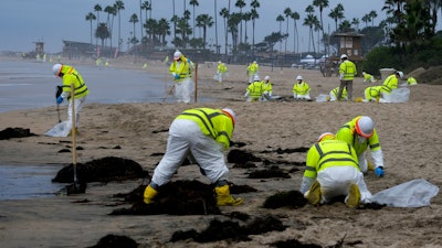 Workers in protective suits clean the contaminated beach in Corona Del Mar after an oil spill in Newport Beach, Calif., Oct. 7, 2021.
