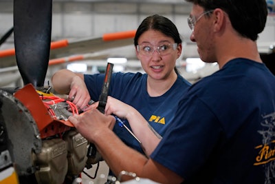 Students at the Pittsburgh Institute of Aeronautics Nikki Reed, center, and William Onderdork study the engine on an Cessna 310 aircraft in West Mifflin, Pa., Tuesday, May 2, 2023. Students graduating from PIA have been awed by how much they're in demand.