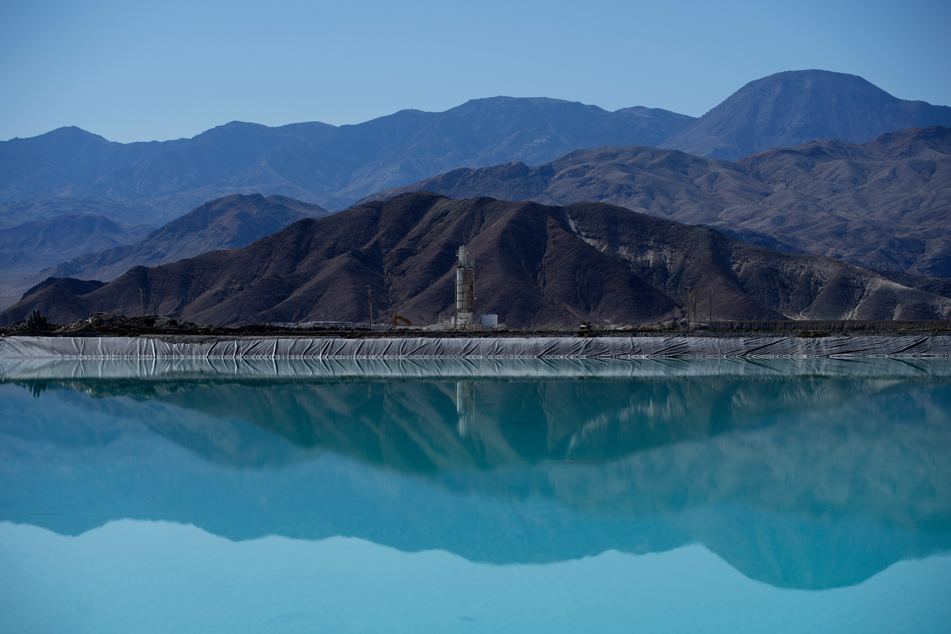 Mountains and a liming facility are reflected in a brine evaporation pond at Albemarle Corp.'s Silver Peak lithium facility, on Oct. 6, 2022, in Silver Peak, Nev.