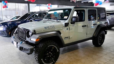 A plug-in hybrid gas/electric Jeep Wrangler is displayed on the showroom floor at the Dan O'Brien Auto Group dealership, Monday, Feb. 27, 2023, in Methuen, Mass. Stellantis says it is pulling together a network of public electric vehicle chargers that could include could include Tesla and nearly all of the other chargers in the U.S., Canada and Europe.