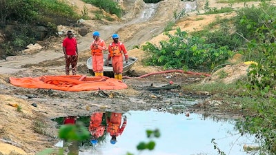 In this grab taken from video, workers stand by a container to collect oil spill waste, in Ogoniland, Nigeria, June 16, 2023. An oil spill at a Shell facility in Nigeria has contaminated farmland and a river. It's upended livelihoods in the fishing and farming communities of part of the Niger Delta, which has long endured environmental pollution caused by the oil industry.