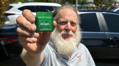 Evan Burroughs, who touts the virtues of an Oregon pilot program that charges motorists by the distance their vehicle travels rather than the gas it uses, displays a tracking device the program uses, in Salem, Ore., on Wednesday June 21, 2023. U.S. states are experimenting with road usage charging programs aimed at one day replacing motor fuel taxes, which are generating less each year, in part due to fuel efficiency and the rise of electric cars.