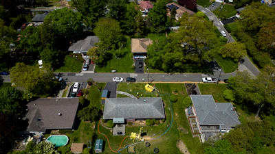 Groundwater empties into a dumpster while workers drill a hole for a geothermal heat pump system at a home in White Plains, N.Y., Monday, May 8, 2023.