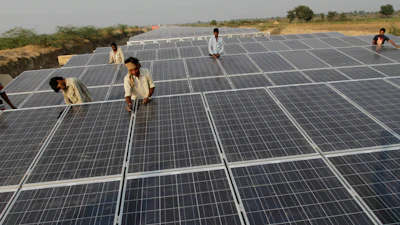 Indian laborers work amid installed solar panels atop the Narmada canal at Chandrasan village, outside Ahmadabad, India, Feb. 16, 2012.