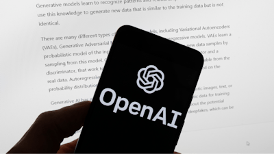 The OpenAI logo is seen on a mobile phone in front of a computer screen displaying output from ChatGPT, March 21, 2023, in Boston.