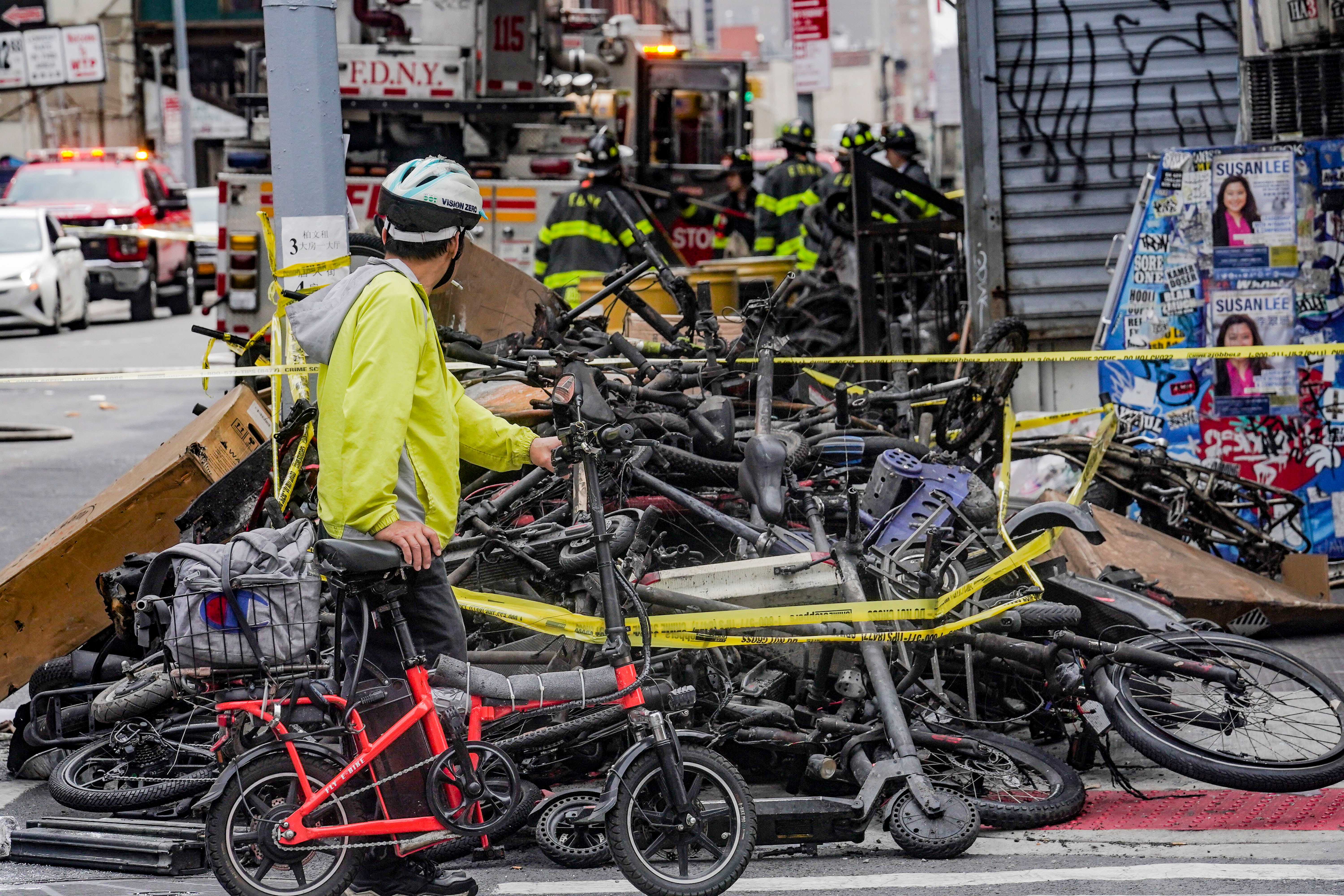 A biker stops to look at a pile of e-bikes in the aftermath of a fire in Chinatown, which authorities say started at an e-bike shop and spread to upper-floor apartments, Tuesday June 20, 2023, in New York.