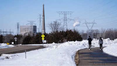 People walk on a trail at the Montissippi County Park near the Xcel Energy Monticello Generating Plant, a nuclear power plant, in Monticello, Minn., on Friday, March 24, 2023.