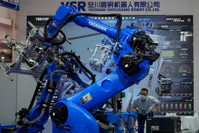 A man looks at the industrial robotic arms from Yaskawa Shougang Robot Co. Ltd on display at the annual World Robot Conference at the Etrong International Exhibition and Convention Center on the outskirts of Beijing, Thursday, Aug. 17, 2023.