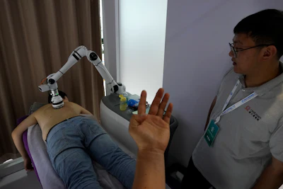 An exhibitor watches a visitor receiving a massage by a robotic arm during the annual World Robot Conference at the Etrong International Exhibition and Convention Center on the outskirts of Beijing, Thursday, Aug. 17, 2023.
