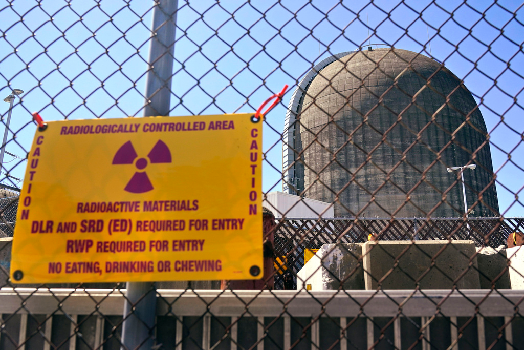 A sign warning of radioactive materials is seen on a fence around a nuclear reactor containment building, April 26, 2021, a few days before it stopped generating electricity at Indian Point Energy Center, in Buchanan, N.Y.