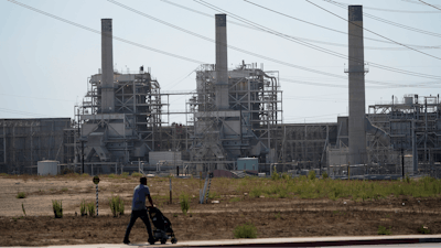 A man pushes a stroller near the AES power plant in Redondo Beach, Calif., Sept. 7, 2022.