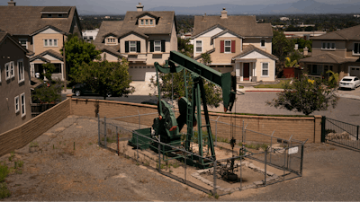 A pump jack extracts oil at a drilling site next to homes June 9, 2021, in Signal Hill, Calif.