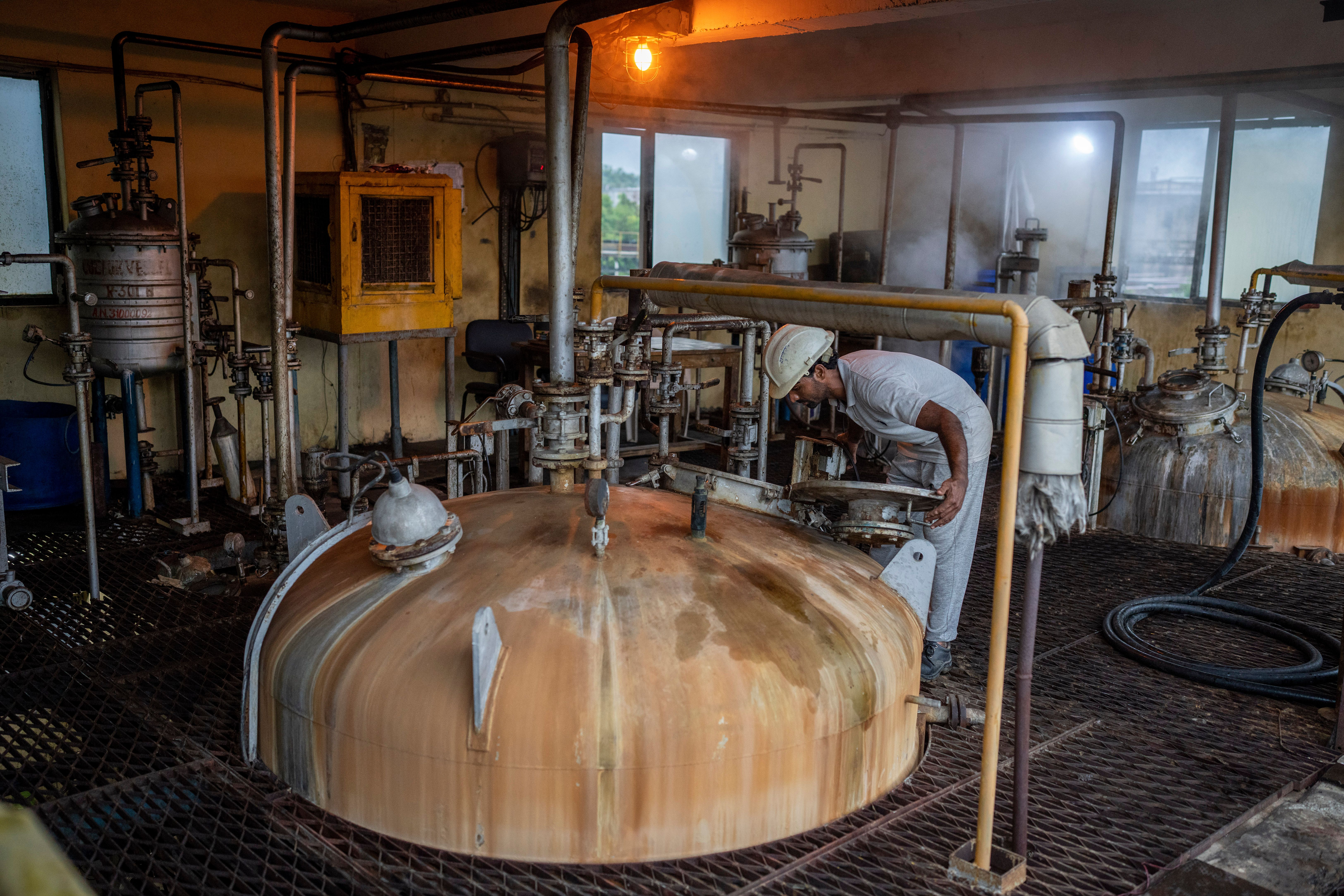 A technician looks through a lid into a culture vessel for yeast development at Bajaj Hindustan Sugar factory that produces ethanol, a type of biofuel, in Meerut, India, Wednesday, Aug. 23, 2023.