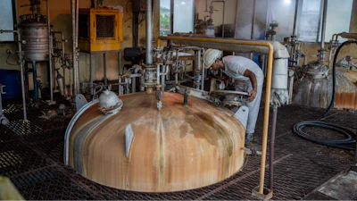 A technician looks through a lid into a culture vessel for yeast development at Bajaj Hindustan Sugar factory that produces ethanol, a type of biofuel, in Meerut, India, Wednesday, Aug. 23, 2023.