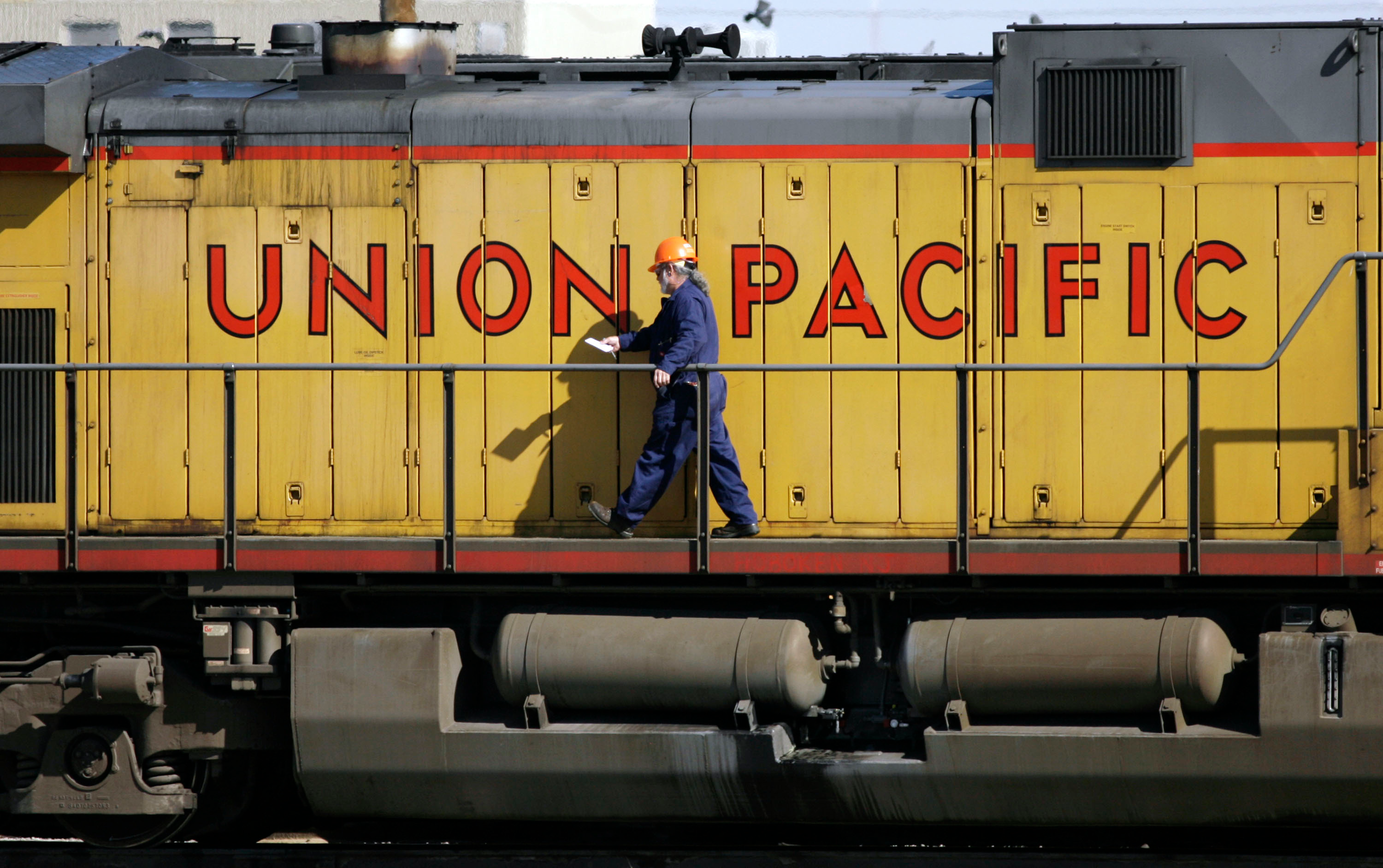 A maintenance worker walks on the side of a locomotive in the Union Pacific Railroad fueling yard, Denver, Oct. 18, 2006.
