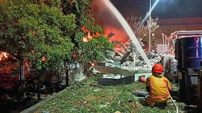 In this image provided by the Pingtung County Government, a firefighter tries to extinguish a fire at a factory of golf ball manufacturer Launch Technologies Co. in the southern county of Pingtung in Taiwan on Friday, Sept. 22, 2023.